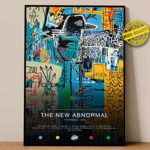 May include: A framed art print of "The New Abnormal" by The Strokes. The artwork features a vibrant abstract design with blue, yellow, and black elements. Text includes the album title, band name, and song titles.