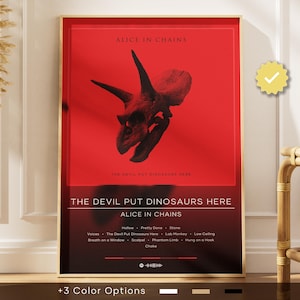 Può includere: Un poster incorniciato con la copertina dell'album "The Devil Put Dinosaurs Here" degli Alice in Chains. Il poster ha uno sfondo rosso con una grafica di teschio di dinosauro nero. Il titolo dell'album e il nome della band sono visualizzati in testo bianco.