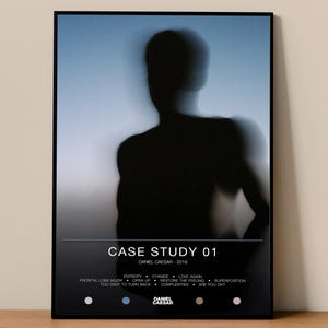 May include: Framed art print featuring a blurred silhouette of a person against a blue and white gradient background. The print includes the text "CASE STUDY 01" and the artist's name, "DANIEL CAESAR - 2019", along with a list of song titles.