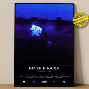 Puede incluir: Un póster enmarcado con un fondo azul oscuro y negro. El póster presenta el texto "NEVER ENOUGH" y "DANIEL CAESAR - 2023". La imagen tiene un diseño borroso y abstracto con una figura blanca. Una pegatina de "HIGH QUALITY" está en la esquina superior derecha.