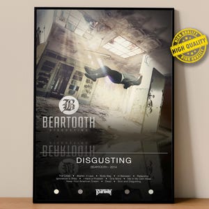 Puede incluir: Un póster enmarcado con el álbum "Disgusting" de la banda Bear Tooth. La imagen muestra a una persona cayendo en un edificio en ruinas. El póster incluye el logotipo de la banda y los títulos de las canciones. Una pegatina de "Alta Calidad" está en la esquina superior derecha.