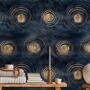 May include: Wallpaper featuring a repeating pattern of gold concentric circles on a dark navy blue textured background. The design includes metallic gold circular motifs layered over a deep blue surface with a subtle, mottled appearance.