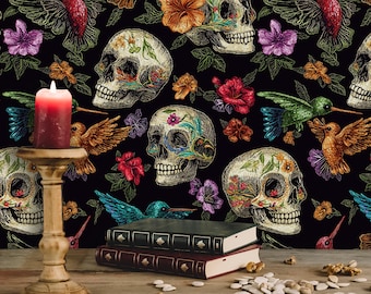 May include: A Day of the Dead themed image featuring a red candle in a wooden candlestick, books, and walnuts on a wooden surface. The background is a repeating pattern of decorated skulls, hummingbirds, and flowers on a black background.