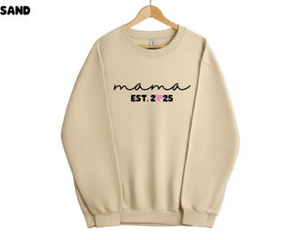 May include: A beige sweatshirt with the text "mama est. 25" in black with a pink heart.