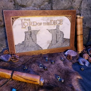 Peut inclure: Un cadre en bois avec un motif gravé et les mots "The Lord of the Dice" sur un fond blanc. Le cadre est posé sur un tapis en fourrure brune avec plusieurs dés noirs et bleus éparpillés autour.