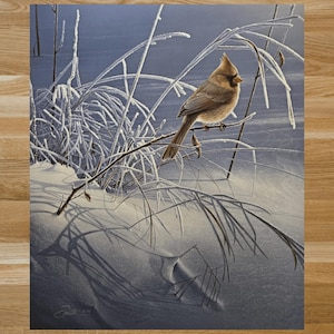 May include: A detailed painting of a bird perched on a branch in a snowy landscape. The bird has brown and tan feathers, and the scene is set against a blue sky. Frost covers the branches and tall grass, creating a winter scene.