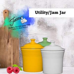 Puede incluir: Tres tarros de cerámica para uso general/mermelada en amarillo, verde y blanco. El tarro amarillo está en primer plano. Los tarros tienen tapas y están sobre una superficie blanca. La imagen incluye el texto "Fiesta" y "Utility/Jam Jar".
