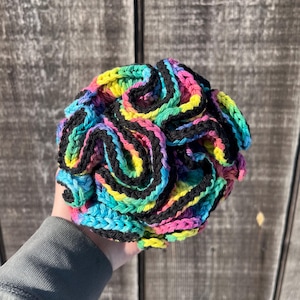 May include: A colorful crocheted ball with black stripes. The ball is made with a variety of colors, including pink, blue, green, and yellow.