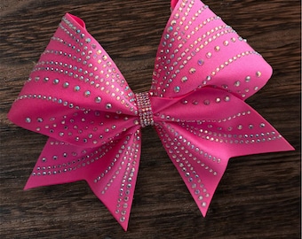May include: A vibrant pink satin hair bow adorned with sparkling rhinestones. The bow features a central rhinestone band and rows of rhinestones that cascade down the bow's loops. This accessory is perfect for adding a touch of glamour to any hairstyle.