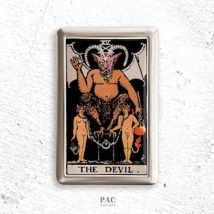 May include: A silver metal case featuring a tarot card design. The card depicts a horned, orange-skinned devil figure seated on a throne, with two nude figures chained below. The text "THE DEVIL" is at the bottom.