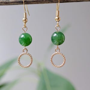 May include: Gold earrings with a green jade stone and a gold circle dangle.