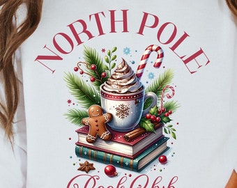 May include: White sweatshirt with a red and white graphic design that says "North Pole Book Club". The graphic features a cup of hot chocolate with whipped cream, a gingerbread man, and a stack of books.