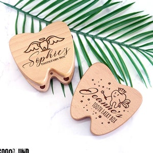 Puede incluir: Dos cajas de dientes de hada de madera con forma de dientes. Una caja tiene un hada de los dientes con alas y el nombre "Sophie's" grabado en ella. La otra caja tiene un hada de los dientes con una corona y una varita m&aacute;gica y el nombre "Jeanne's" grabado en ella.