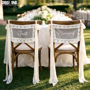 Puede incluir: Dos sillas de madera con cojines color crema y respaldos adornados con encaje y cintas. Los respaldos tienen paneles grises con las palabras "Just" y "Married" en escritura elegante, para una boda.