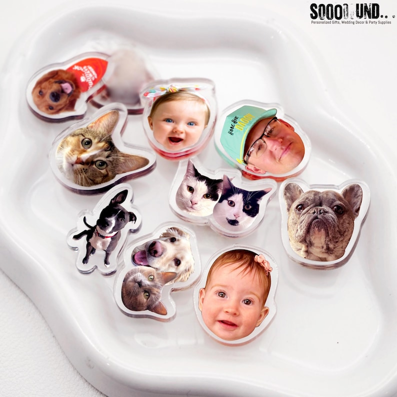 May include: A collection of clear acrylic personalized photo magnets featuring images of pets, babies, and people. The magnets are in various shapes and sizes, with a white border. The background is a white, curved tray. The text "SOOOO SOUND..." is visible in the top right corner.
