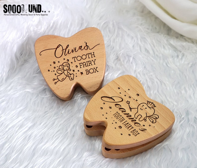 Puede incluir: Dos cajas de dientes de hada de madera con forma de dientes. Las cajas est&aacute;n grabadas con los nombres "Olivia's" y "Jeanne's" y presentan un dise&ntilde;o de hada de los dientes con estrellas.