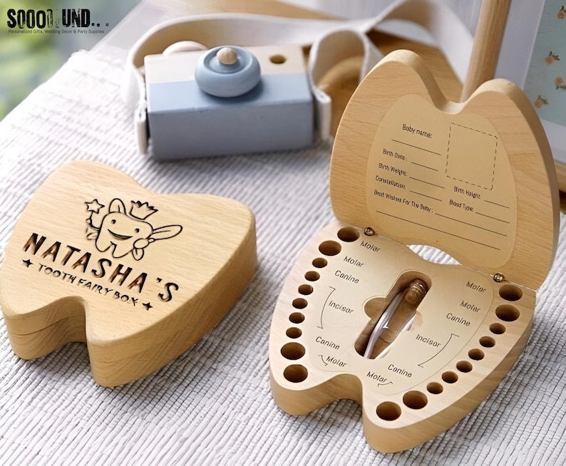 Puede incluir: Una caja de dientes de hada de madera con forma de diente con una ranura para un diente. La caja est&aacute; grabada con las palabras "Natasha's Tooth Fairy Box" y un hada de los dientes de dibujos animados. La caja est&aacute; abierta y tiene una tabla para registrar los dientes del beb&eacute;.