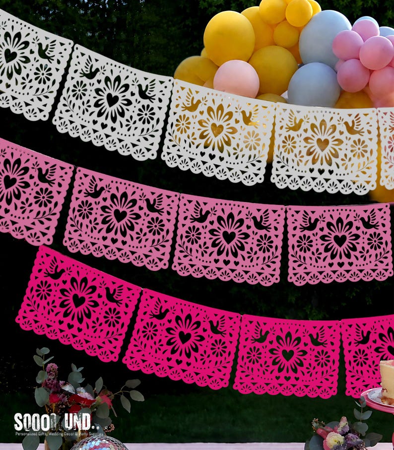 May include: A decorative banner featuring three rows of rectangular paper panels in white, light pink, and hot pink. Each panel displays a symmetrical cut-out design of a central flower, a heart, and two birds, finished with a scalloped bottom edge.