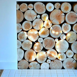 An unused empty fireplace filled with a stack of real wood neat clean decorative logs from The Log Basket and decorated with a large white LED star shaped light that's hung on the front of the stack for Christmas.