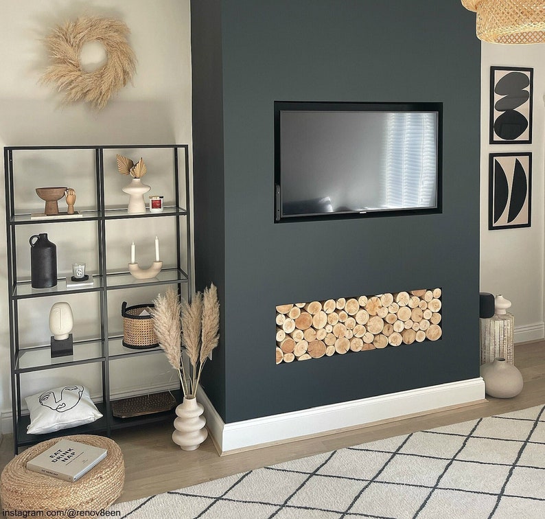 A dark painted chimney breast media wall with a letterbox shaped alcove that has been filled with a stack of real natural wood neat round decorative logs from The Log Basket to create a stylish feature in any home interior unused fireplace or alcove.