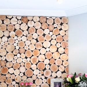 A unique large log wall feature created in a customer's home using log wall tiles from The Log Basket. A simple DIY project, the natural wood discs are fixed to a black panel to enhance the effect. The wooden tiles are different diameters depending on the size of the tree trunks they were cut from. The wood colouring is left as it is naturally, ranging from pale wood to warm dark hearts. The edges of the panel are neatened using the half slices that are included, to achieve a bespoke finish.