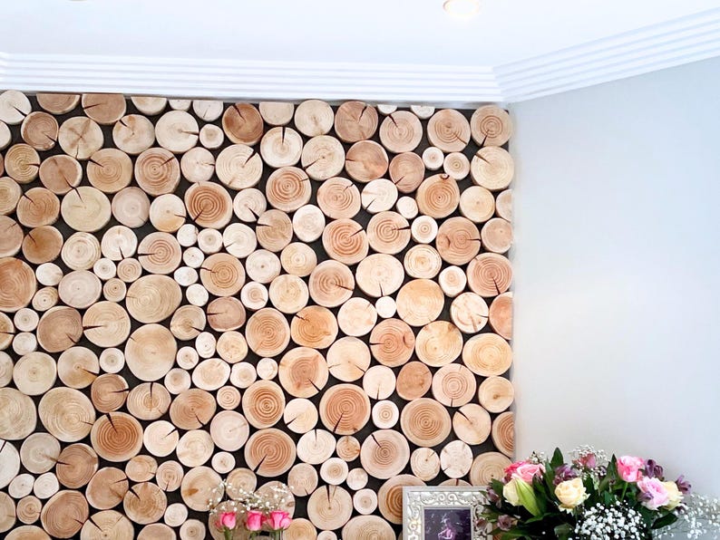 A unique large log wall feature created in a customer's home using log wall tiles from The Log Basket. A simple DIY project, the natural wood discs are fixed to a black panel to enhance the effect. The wooden tiles are different diameters depending on the size of the tree trunks they were cut from. The wood colouring is left as it is naturally, ranging from pale wood to warm dark hearts. The edges of the panel are neatened using the half slices that are included, to achieve a bespoke finish.