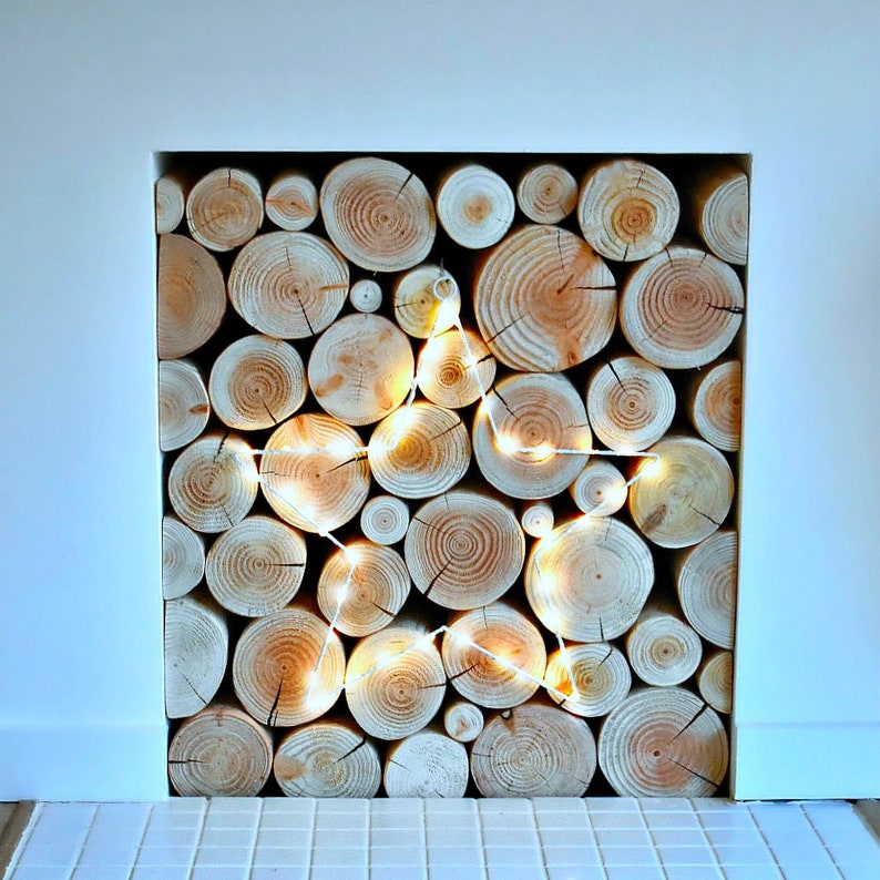 An unused empty fireplace filled with a stack of real wood neat clean decorative logs from The Log Basket and decorated with a large white LED star shaped light that's hung on the front of the stack for Christmas.