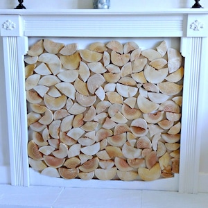 May include: A white fireplace mantel with a decorative wood panel made of many small, round pieces of wood arranged in a pattern. The wood is a light brown colour.