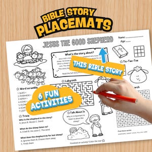 May include: A white Bible story placemat with the text "Bible Story Placemats" and "Jesus the Good Shepherd." The placemat features illustrations of sheep, a shepherd, and various activities, including a word scramble and a maze. A hand is drawing on the placemat.