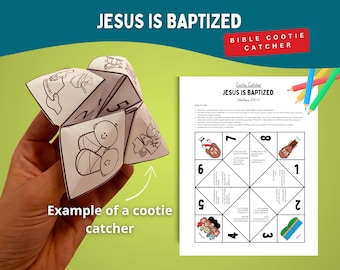Op de afbeelding: Een witte papieren Bijbel-thema kietelaar met de tekst "JESUS IS GEDOOPT" en illustraties. Een afgedrukt vel met instructies en genummerde prompts is ook zichtbaar. Gekleurde potloden staan op de achtergrond.