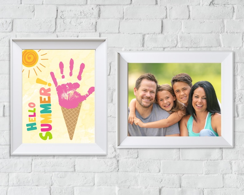 May include: Two white picture frames on a white brick wall. The frame on the left has a colourful illustration of an ice cream cone with the text "Hello Summer!" The frame on the right has a photo of a family of four smiling at the camera.