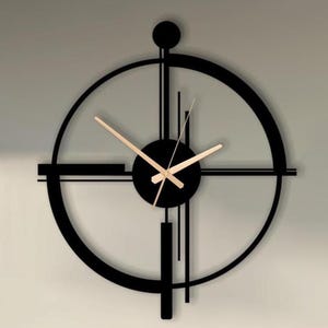 Puede incluir: Un reloj de pared moderno de metal negro con un diseño circular y una estética minimalista. El reloj presenta una esfera negra con manecillas doradas y un patrón geométrico único. Está montado en una pared clara sobre un sofá.