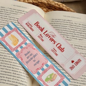Puede incluir: Dos marcapáginas decorativos con estética vintage. Uno es rosa con el texto "Book Lovers Club" y "Admit One". El otro es de rayas azules y blancas con el texto "Books are my favorite place to escape". Ambos tienen marcos ornamentados.