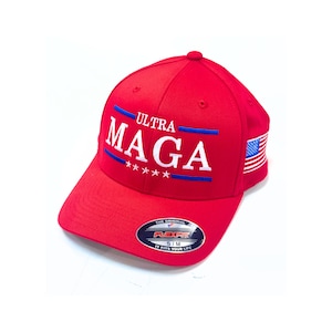 May include: Red baseball cap with the text "ULTRA MAGA" in white with blue accents and four stars. The cap has a small American flag on the side and a "Flexfit" label on the bottom.