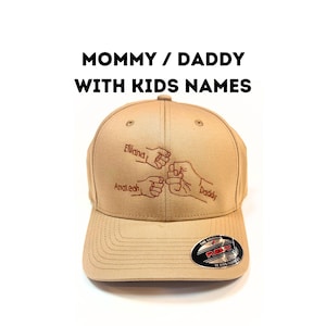 May include: A tan baseball cap with a red embroidered design of four fists bumping each other. The text "Mommy/Daddy with Kids Names" is printed above the design. The names "Ellland", "Analeah", and "Daddy" are embroidered on the fists.