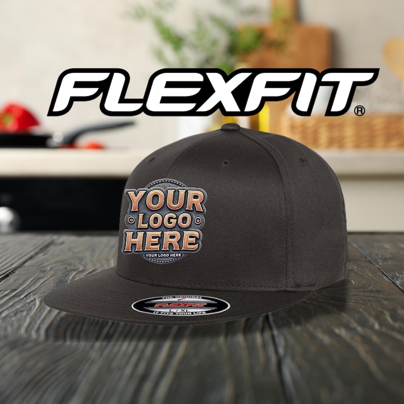 May include: A dark grey Flexfit baseball cap with a flat peak. The cap has a custom logo design that reads "YOUR LOGO HERE" in a vintage style. The Flexfit logo is displayed above the cap.
