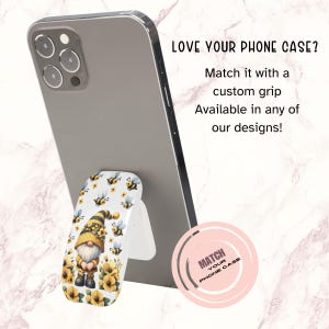 May include: A white phone case with a bee and flower design. The phone case is attached to a white phone grip with a bee and flower design. The phone grip is attached to a black iPhone. The text "LOVE YOUR PHONE CASE? Match it with a custom grip Available in any of our designs!" is displayed above the phone. The text "MATCH YOUR PHONE CASE" is displayed in a pink circle below the phone.