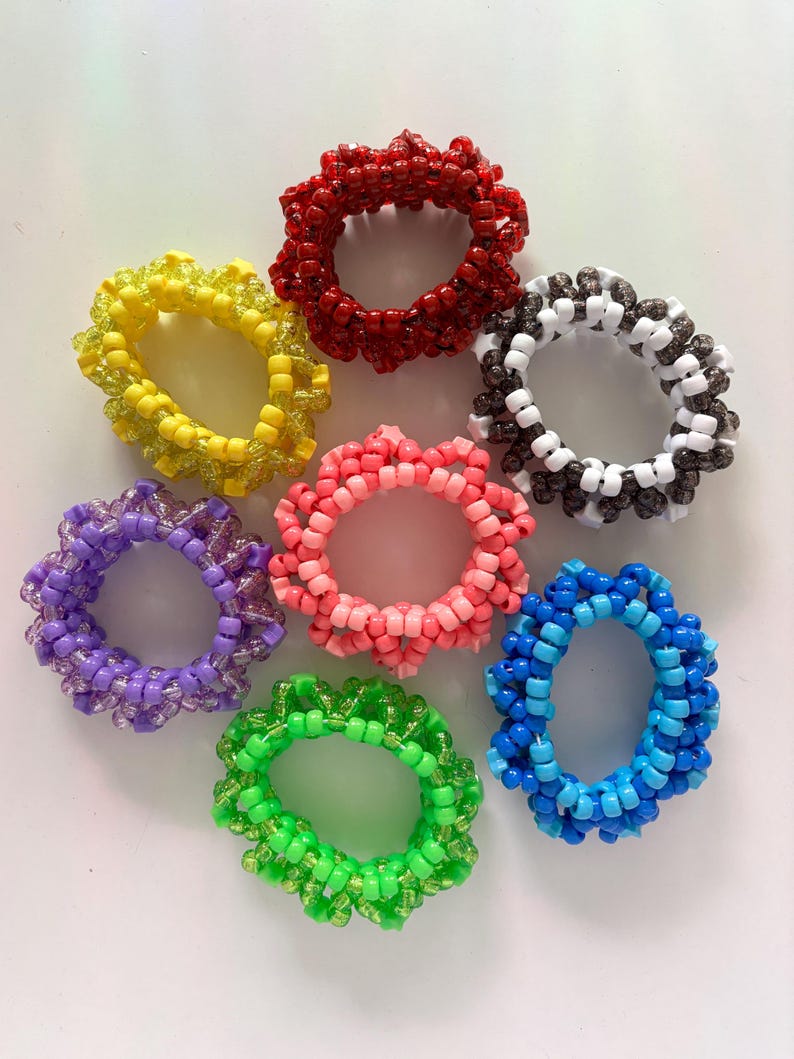 Puede incluir: Siete gomas para el pelo de cuentas de colores en varios colores, incluyendo rojo, amarillo, rosa, morado, blanco, negro y azul.