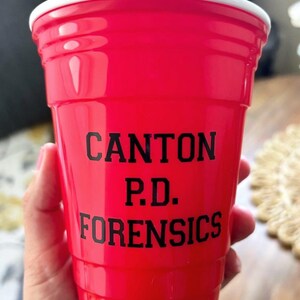 Może przedstawiać: Jasnoczerwony plastikowy kubek z nadrukowanym czarnym tekstem "CANTON P.D. FORENSICS".