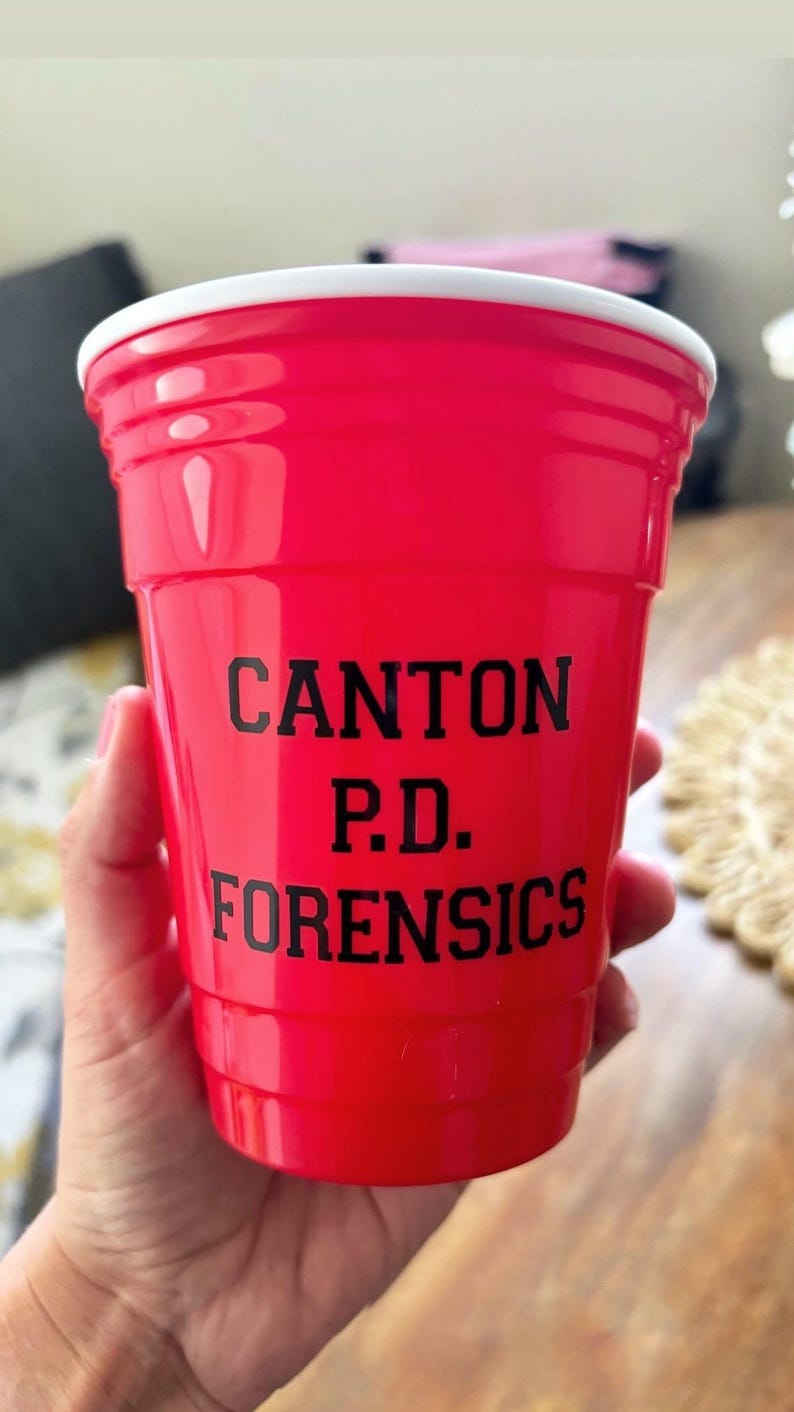 Może przedstawiać: Jasnoczerwony plastikowy kubek z nadrukowanym czarnym tekstem "CANTON P.D. FORENSICS".
