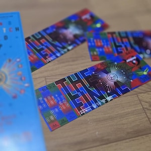 Op de afbeelding: Een blauw boek met de titel "422 Quidditch World Cup" met gouden details en verschillende kleurrijke tickets met de tekst "THE FINAL" in een levendig ontwerp. De items liggen op een houten oppervlak.