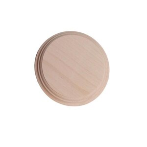 Puede incluir: Una placa redonda de madera sin terminar con un borde decorativo en relieve. La veta de la madera de color claro es visible en toda la superficie. Este suministro artesanal es ideal para pintar, grabar u otros proyectos de bricolaje.