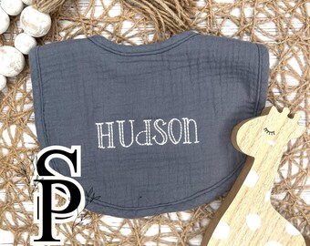 May include: Gray cotton baby bib with the name "Hudson" embroidered in white thread.