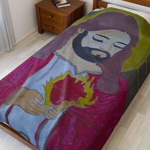 May include: A bedspread with a painted image of a religious figure with a beard and long hair, holding a flaming heart. The figure is depicted in red, white, and brown tones, with a yellow halo. The bedspread is on a wooden bed frame.