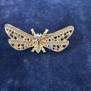 以下が含まれることがあります： 虹色のピンクとクリアなラインストーンが施された蝶の形をしたゴールドトーンのブローチ