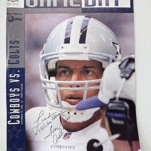 May include: A vintage Dallas Cowboys vs. Colts game day program cover. The cover features a football player in a silver helmet and jersey. The program includes the text "GAME DAY", "COWBOYS VS. COLTS", and "SEPTEMBER 15, 1996".