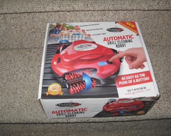 Nuevo robot limpiador automático de parrillas Grillbot sellado con cepillos de nailon rojos. Incluye cargador.