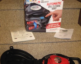 Robot limpiador automático de parrillas Grillbot nuevo con cepillos de nailon de color rojo. Incluye cargador y estuche rígido.