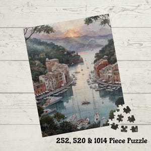 May include: A jigsaw puzzle depicting a coastal town scene with buildings, boats, and a sunset. The puzzle includes the text "252, 520 & 1014 Piece Puzzle". The image features a watercolor style with muted colors and a detailed harbor view.