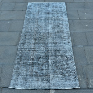 Op de afbeelding: Een vintage blauw en wit tapijt met een verweerde look. Het tapijt heeft een verbleekte, versleten uitstraling, wat het een uniek karakter geeft.